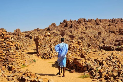 Man in blue boubou among the ruins of the fortified trading post or Ksar