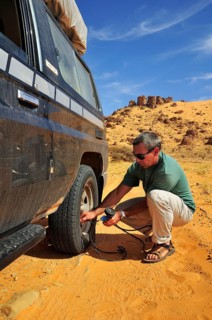 Man letting air out of the tires before driving on a road with soft sand
