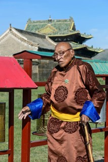 Old man in traditional Mongolian costume with Buddhist prayer beads in left hand