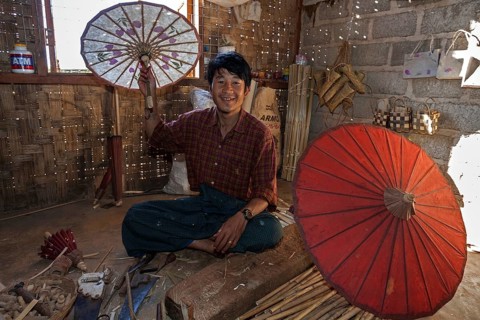 Local man with finished umbrellas in an umbrella factory