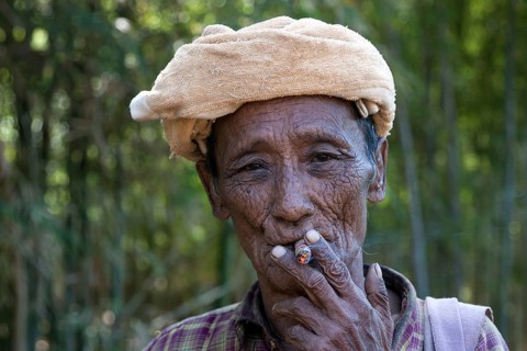 Old local man with headgear smoking a cigar