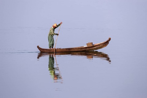 Local man on a wooden boat on the Taungthaman lake