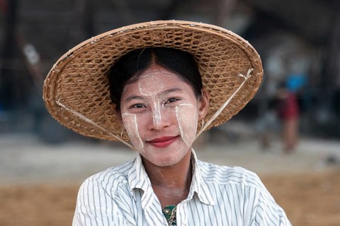 Local woman wearing a straw hat and Thanaka paste on her face