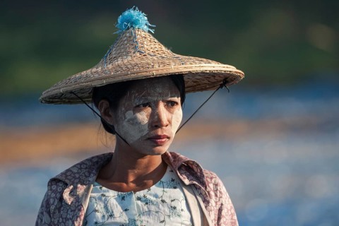 Local woman with straw hat and Thanaka paste on her face