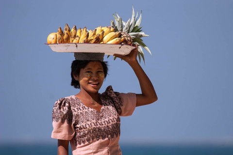 Native woman with a bowl of bananas on her head and Thanaka paste on her face