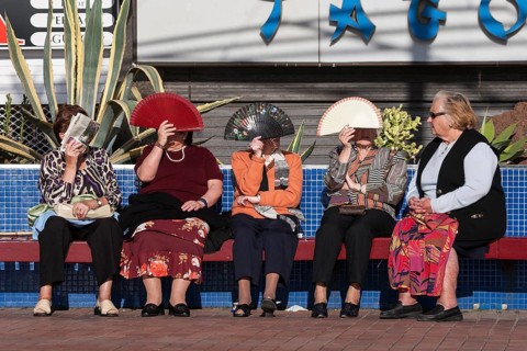 Women protecting their faces from the sun with fans