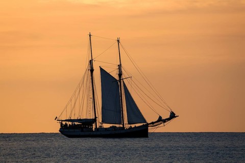 Sailboat in the Beau Vallon Bay in front of an orange sky