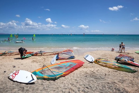 Windsurfing boards and sails lying on the beach