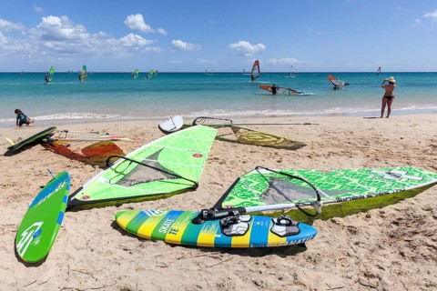 Windsurfing boards and sails lying on the beach