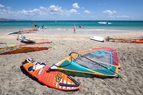 Windsurfing boards and sails lying on the beach