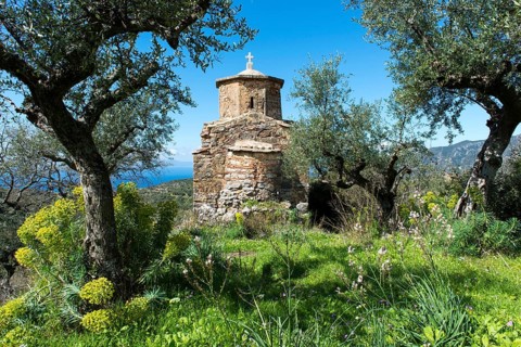 Small Greek Orthodox Church in a mountain village on the coast surrounded by olive trees
