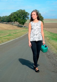 Young brunette with petrol can walking on country road