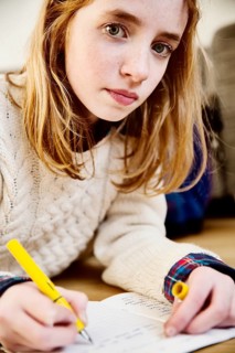 Girl doing her homework on the floor at home