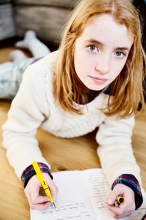Girl doing her homework on the floor at home