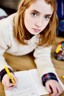 Girl doing her homework on the floor at home