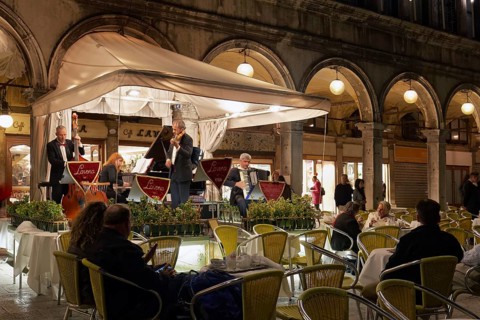 Musician on podium in front of Gran Caffe Laveno at night