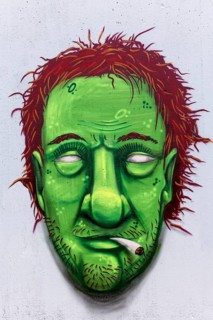 Portrait of a man with a green face smoking weed