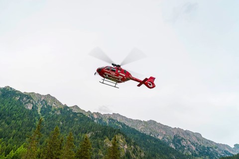 Red Aiut Alpin rescue helicopter I-AIUT taking off from meadow