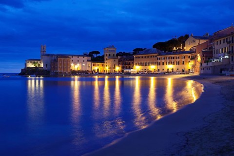 Town beach in the bay Baia del Silenzio with Chiesa di San Nicolo church
