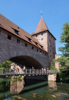 Kettensteg chain-hung bridge and Fronveste with Schlayerturm tower above river Pegnitz