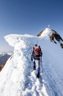 Mountaineer climbing in the snow on the Wildspitze on the summit ridge with snow cornice