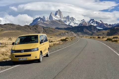 VW bus on the road to El Chalten in front of a mountain range with striking Monte Fitz Roy