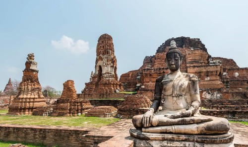 Dilapidated temple complex with large stupa and Buddha statue