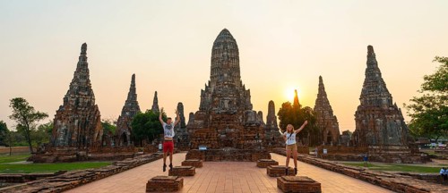 Two tourists jumping in front of a Buddhist temple