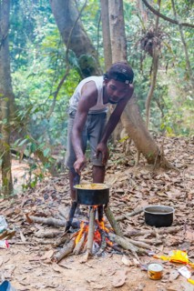Man of the Orang Asil cooking food on a fire in the jungle