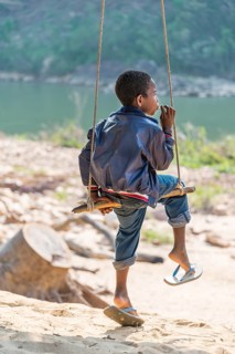 Young Orang Asil boy swinging and looking into the distance