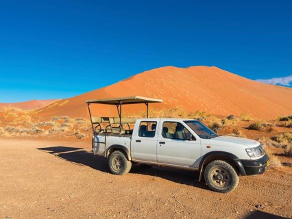 Terrain vehicle in front of a sand dune of the Namib Desert