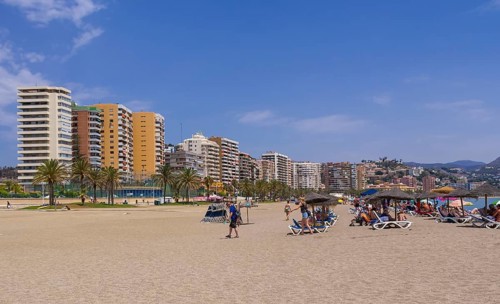 Deck chairs on the beach and skyscrapers behind at Playa de la Malagueta