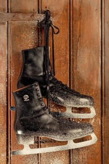 Old ice skates hanging on a wooden door with snowflakes
