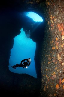 Diver with lamp in a rocky cave