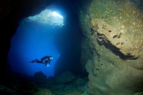 Diver with lamp in rocky cave