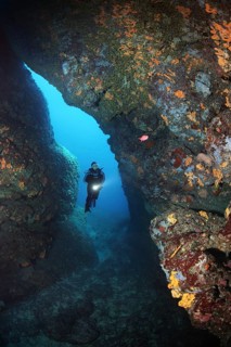 Diver with lamp in rocky cave