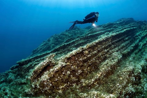 Diver observing layers of rock on shelf