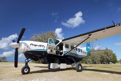 Cessna Caravan 208 Sea Air on unpaved airfield with open underfloor luggage lockers