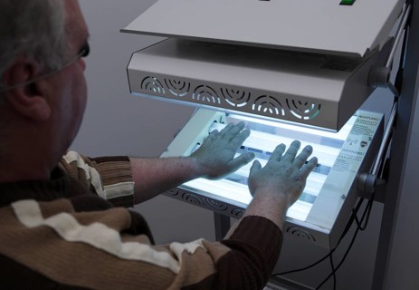 Patient has his hands in a phototherapy box for an irradiation treatment