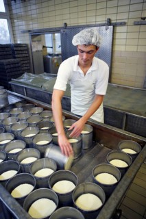 Dairy expert is filling curd into moulds at the Sarzbuttel fine cheese dairy