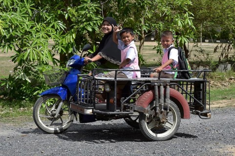 Woman wearing a headscarf and school children on a scooter
