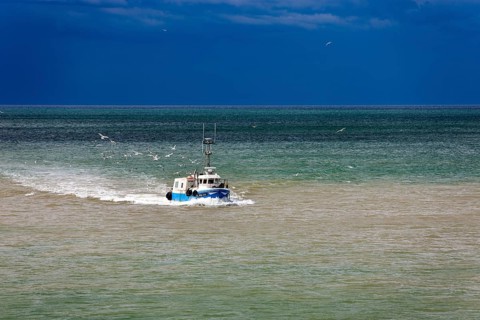 Fishing boat in the sea in front of storm front in Saint-Valery-en-Caux