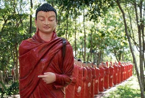 Statues of monks walking behind Buddha