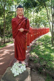 Statues of monks walking behind Buddha