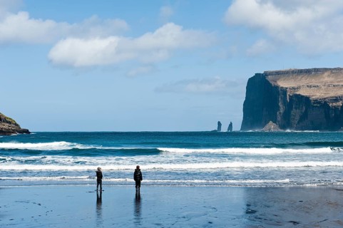 Two people on the black sand beach of Tjornuvik