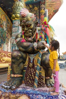 Girl rubbing bill at a Yaksa statue
