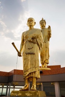 Golden statues of Buddha and monk Luang Phor Khoon on the roof of the Elephant Temple Thep Wittayakhom Vihara