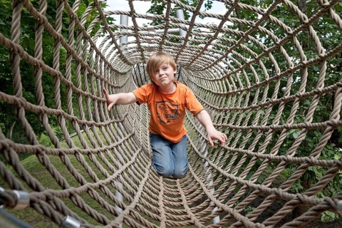 Boy crawling through a rope tunnel