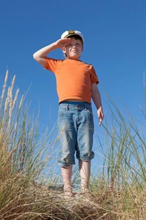 Boy wearing captain's hat on dunes