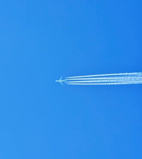 Aibus 380 widebody aircraft of Qatar Airlines with contrails in blue sky